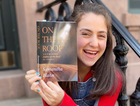 Samantha Hahn poses with her book "On The Roof: A Look Inside _Fiddler on the Roof_ in Yiddish." by the Forward
			