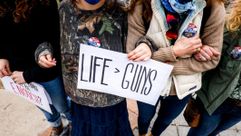 A woman holds a sign as people link arms at a gun reform rally at the Colorado State Capitol in Denver, March 28, 2021. (Michael Ciaglo/Getty Images) by the Forward
			