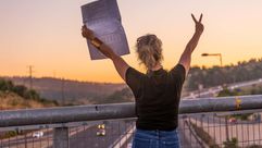 A woman holds a peace demonstration sign on on the Hemed Bridge, near Abu Gosh, Israel. by the Forward
			