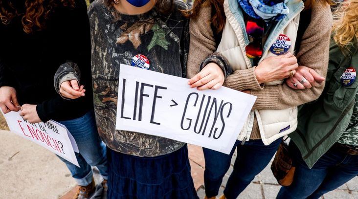 A woman holds a sign as people link arms at a gun reform rally at the Colorado State Capitol in Denver, March 28, 2021. (Michael Ciaglo/Getty Images)