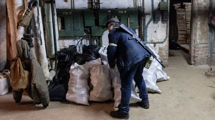 A civilian member of a Territorial Defence unit carries bags of bottles to be made into molotov cocktails in a basement on February 26, 2022 in Kyiv, Ukraine. (Chris McGrath/Getty Images)