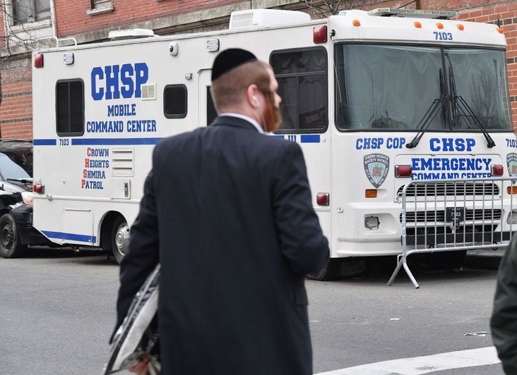 An Orthodox Jew walks past a 'Crown Heights Shmira Patrol' security vehicle in the Brooklyn neighborhood of Crown Heights after they experienced acts of antisemitism in 2019.