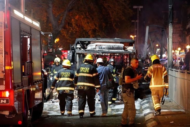 Israeli firefighters check out a burnt bus in the Israeli town of Holon near Tel Aviv, on May 11, 2021, after rockets are launched towards Israel from the Gaza Strip.