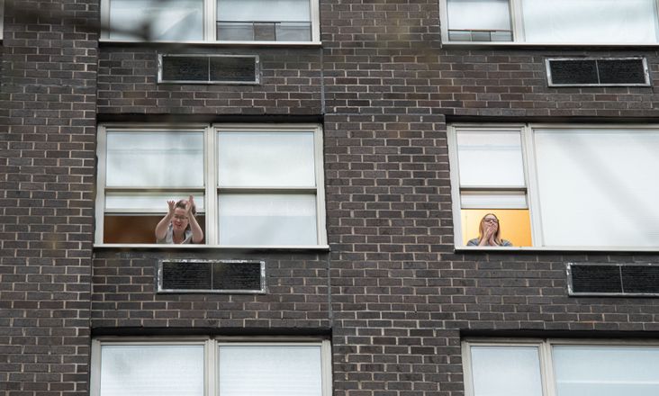 People cheering medical staff and essential workers from their windows.