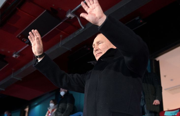 Vladimir Putin stands with his hands raised at the Olympics