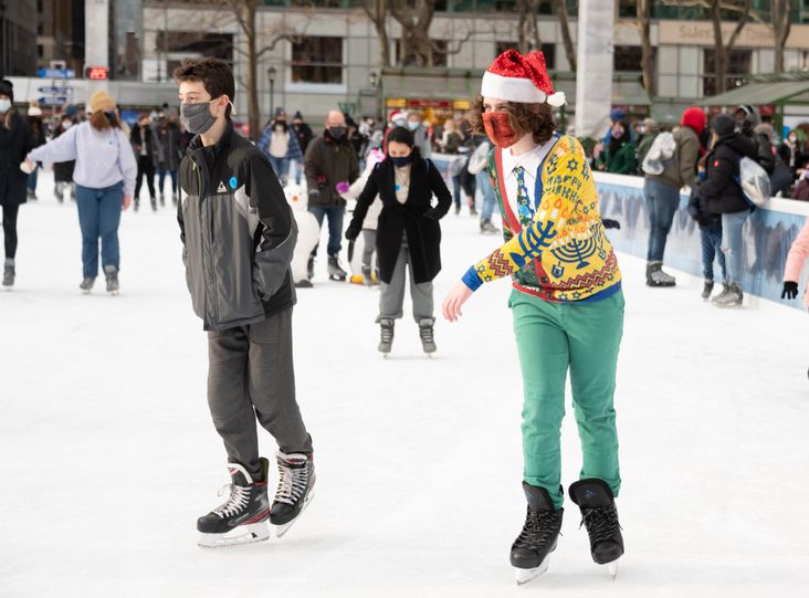 A person wears a Hanukkah and Christmas sweater while ice skating at Bank of America Winter Village in Bryant Park.