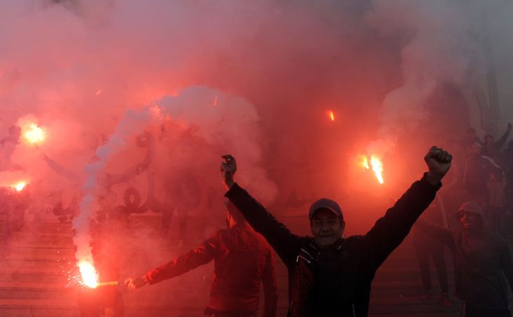 Tunisian protesters carry flares and shout slogans during celebrations in central Tunis on January 14, 2018,
