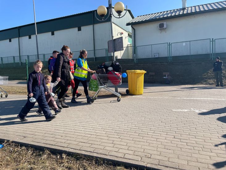 A refugee family heads for the border, pushing a shopping cart