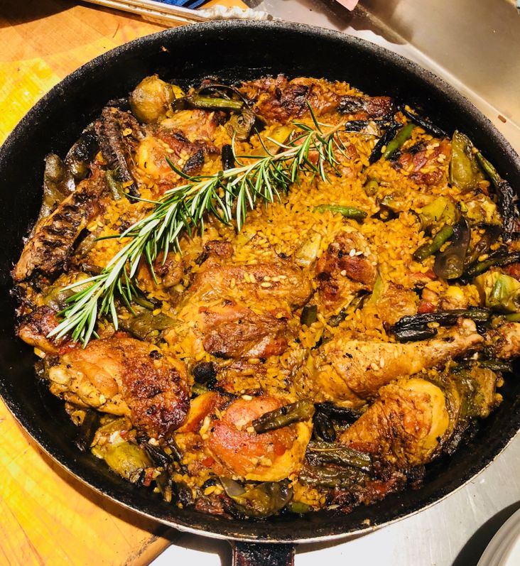 Paella with chicken and artichokes cooked over a wood fire.