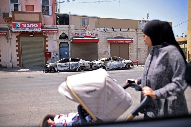 An Arab Israeli woman looks on May 11, 2021 at burnt cars in the central Israeli city of Lod, near Tel Aviv.