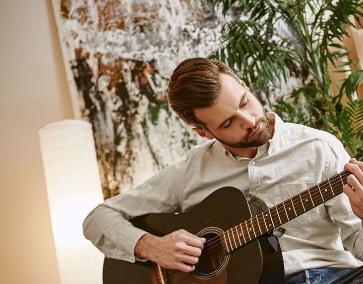 A man plays guitar for an online upload.