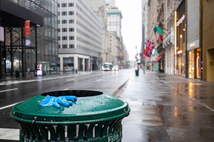 Empty New York streets on a rainy day, with a discarded medical glove on a trashcan's edge.