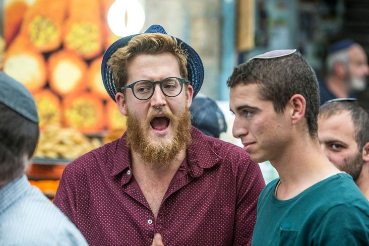 Two men, one in a hat and one in a kippah, at a market in Jerusalem.