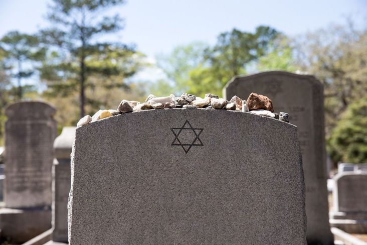 A Jewish headstone with rocks set on it.