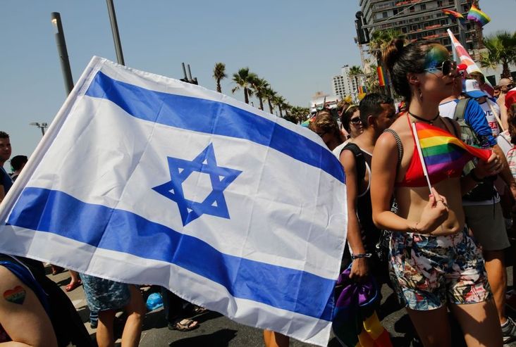 Revellers carrying an Israeli national flag celebrate along a sea side avenue in Tel Aviv during the city's annual Gay Pride parade on June 8, 2018.